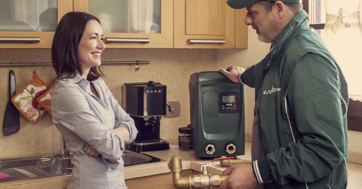DAB Esybox Mini3 compact water pressure system being installed in an apartment kitchen.